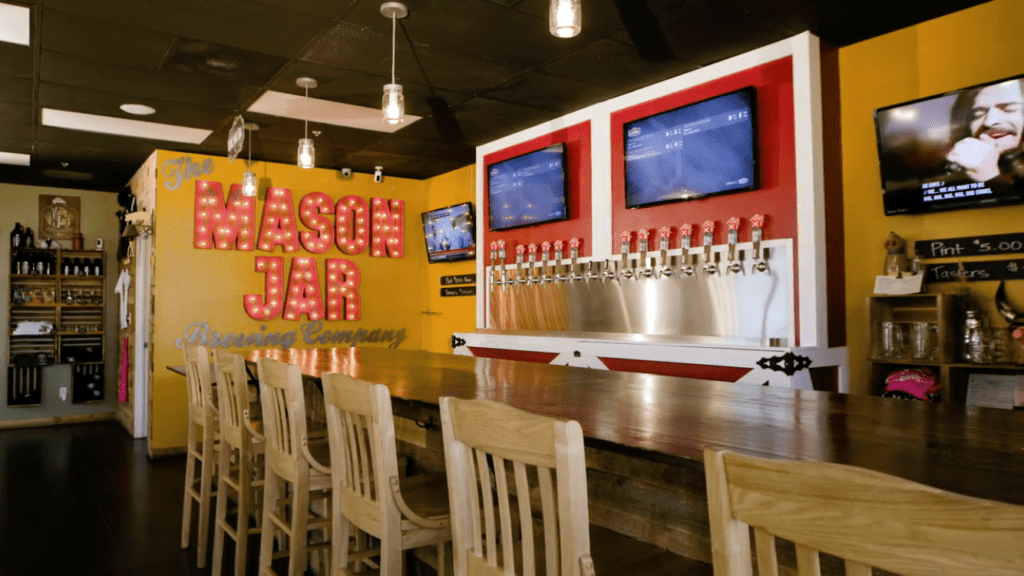 The bar faces a row of draft beer taps and flatscreen TVs at Mason Jar Brewing Company
