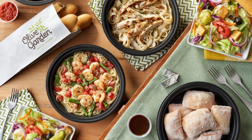 Shrimp scampi, salad, chicken alfredo, breadsticks and clean place settings on sage linen are pictured in this Olive Garden promotional image