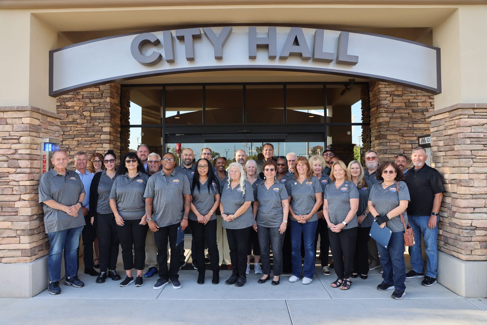 A group of people stands in front of a building with a City Hall sign, posing for a group photo as part of the Menifee Citizens' Academy.